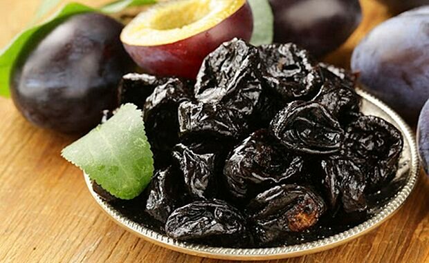 Dried plums prunes and fresh berries on the wooden table